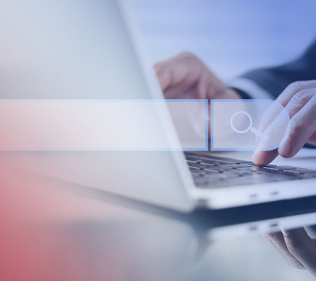 Ein aufgeklappter Laptop befindet sich auf einem Schreibtisch. Eine Person tippt etwas in den Laptop ein. Die Person ist nur im Anschnitt dargestellt. Halbtransparent erkennt man im Vordergrund ein Eingabe- bzw. Suchfeld. Die Simba ERP Software erleichtert die Prozesse der Unternehmensführung. 