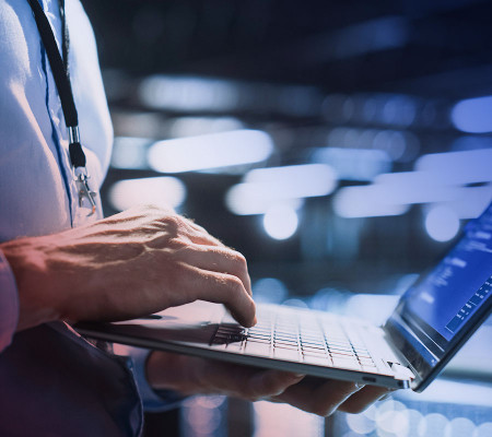 Eine Person hält einen Laptop in der Hand und tippt mit seiner rechten Hand. Die Simba ERP Software optimiert Prozesse in der Material- und Produktionsplanung – die effiziente Gestaltung der Prozesse wird in diesem Bild dargestellt. 